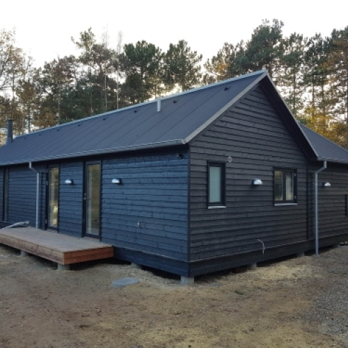 Færdig tilbygning til hus i træ med mørk facade og nyt tag