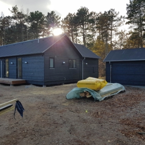 Ny tilbygning på hus med sort facade og tilhørende anneks