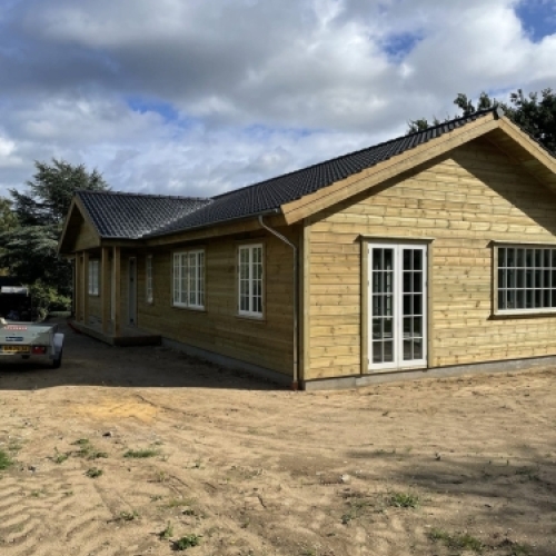 Tilbygning til træhus med nye vinduer, døre og mørkt tag