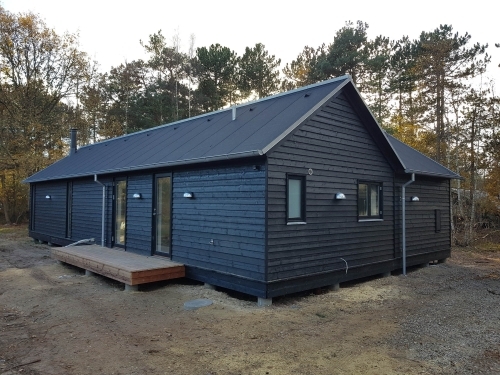 Færdig tilbygning til hus i træ med mørk facade og nyt tag