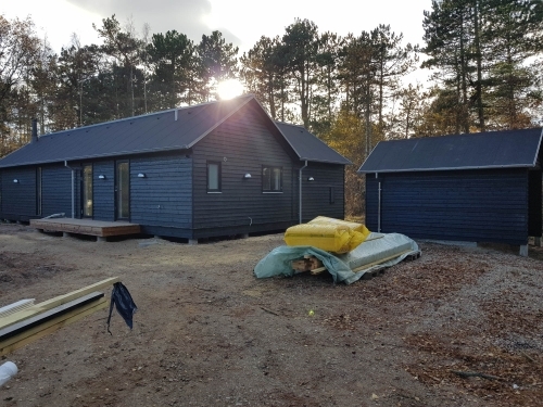 Ny tilbygning på hus med sort facade og tilhørende anneks