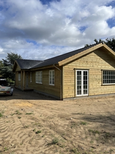 Tilbygning til træhus med nye vinduer, døre og mørkt tag