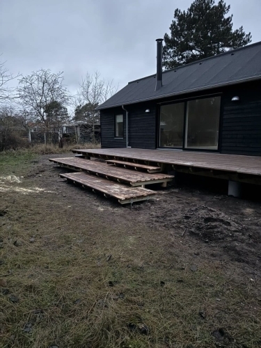 Træterrasse opbygning med trappetrin foran hus med mørk facade